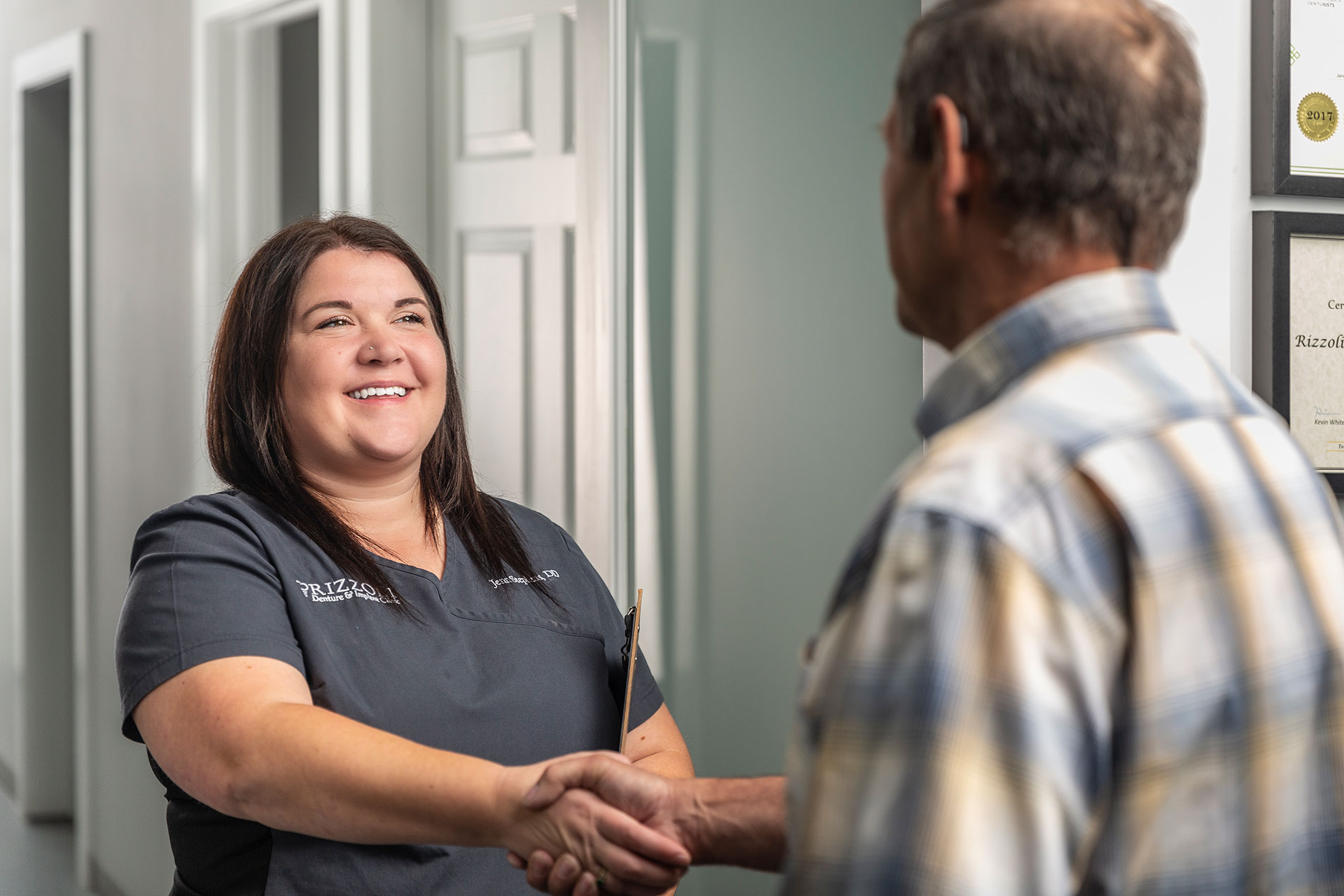 A happy patient at the Rizzoli Denture Clinic shaking hands with a denturist